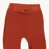 A close up of the Little Green Radicals ginger knitted leggings showing the elasticated waist band and drawstring detail on dark orange organic cotton fabric