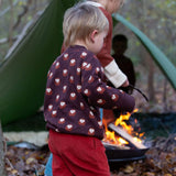 A child in a campsite outdoors wearing the LIttle Green Radicals brown owl knitted jumper. A soft knit GOTS organic cotton jumper in brown with cute owls. 