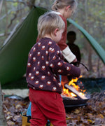 A child in a campsite outdoors wearing the LIttle Green Radicals brown owl knitted jumper. A soft knit GOTS organic cotton jumper in brown with cute owls. 