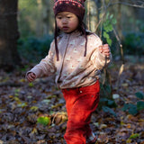 A child wearing the soft pink Little Green Radicals knitted cardigan in puddle ducks outside. Showing the length and fit of the cardigan. 