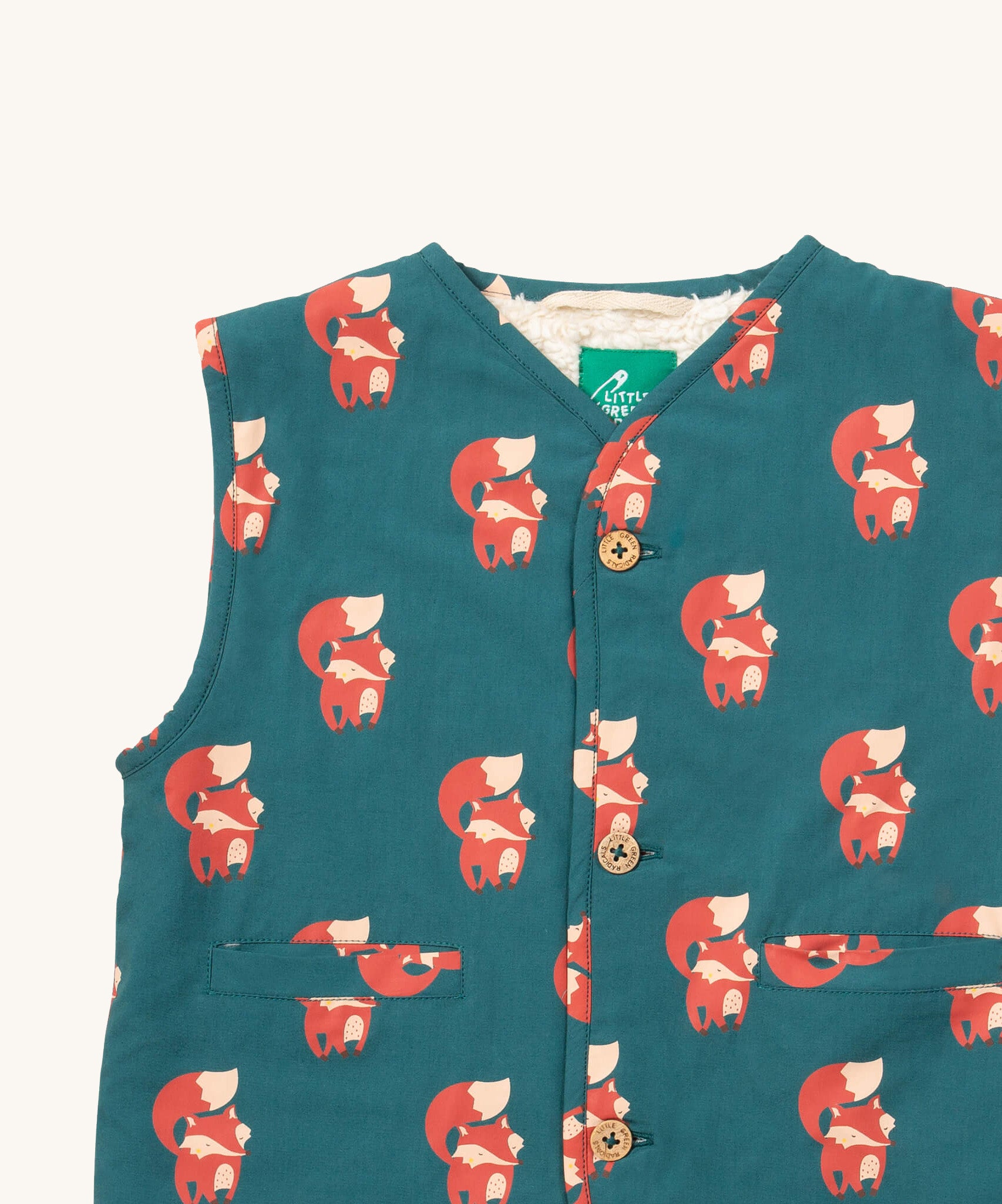 A close up of the Little Green Radicals reversible gilet in red foxes and sherpa lined. Showing the button detail and a close up of the cute fox print on GOTS organic cotton fabric. 