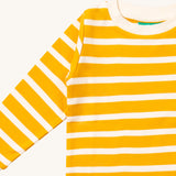 A close up of the Little Green Radicals gold striped long sleeve top that's available at Babipur. Showing the yellow and white stripe detail on organic cotton fabric.