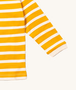 A close up of the Little Green Radicals gold striped long sleeve top that's available at Babipur. Showing the white cuff detail on striped organic cotton fabric.