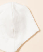 A close up of the Little Green Radicals baby hat showing the side stitching detail on white organic cotton fabric