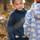A child wearing the Little Green Radicals navy sheep snuggle knitted jumper at Babipur. A navy GOTS organic cotton jumper with white speckles and cute sheep knitted in the jumper 