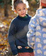 A child wearing the Little Green Radicals navy sheep snuggle knitted jumper at Babipur. A navy GOTS organic cotton jumper with white speckles and cute sheep knitted in the jumper 