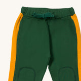 A close up the Little Green Radicals olive cosy joggers showing the drawstring detail, 2 side pockets and stitched on knee patches  on green organic cotton fabric.