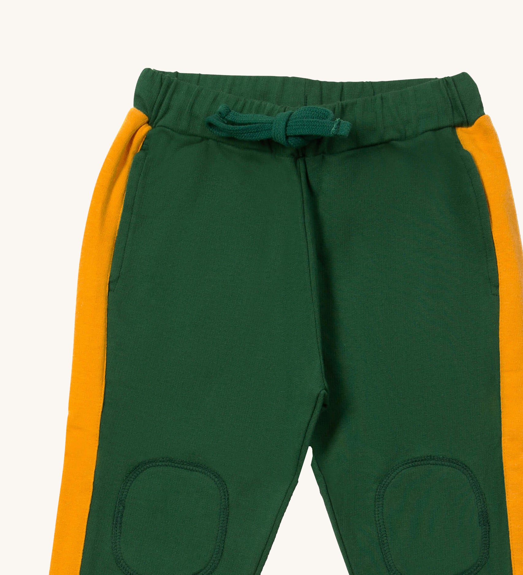 A close up the Little Green Radicals olive cosy joggers showing the drawstring detail, 2 side pockets and stitched on knee patches  on green organic cotton fabric.