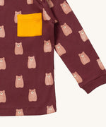 A close up of the Little Green Radicals brown bear sleeve t-shirt. Showing the elasticated cuff detail and yellow pouch pocket detail on dark maroon organic cotton fabric