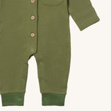 A close up of the Little Green Radicals green chive waffle playsuit showing the button and popper fastener detail on green waffle organic cotton fabric