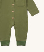 A close up of the Little Green Radicals green chive waffle playsuit showing the button and popper fastener detail on green waffle organic cotton fabric