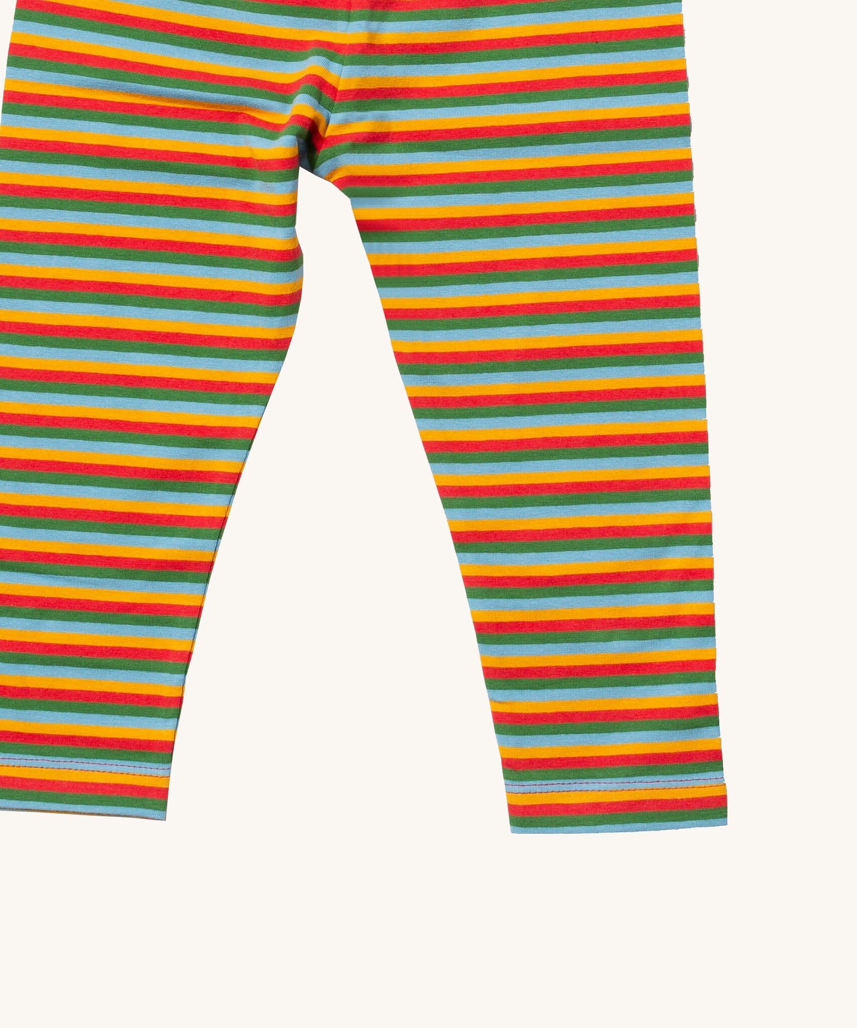A close up of the Little Green Radicals rainbow striped organic leggings. Showing the rainbow striped design  and leg cuff detail on organic cotton fabric