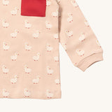 A close up of the Little Green Radicals puddle ducks sleeve t-shirt. Showing the cute duck prints and red pouch pocket detail on peach organic cotton fabric