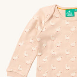 A close up of the Little Green Radicals puddle ducks sleeve t-shirt. Showing the cute duck prints collar trim detail on peach organic cotton fabric.
