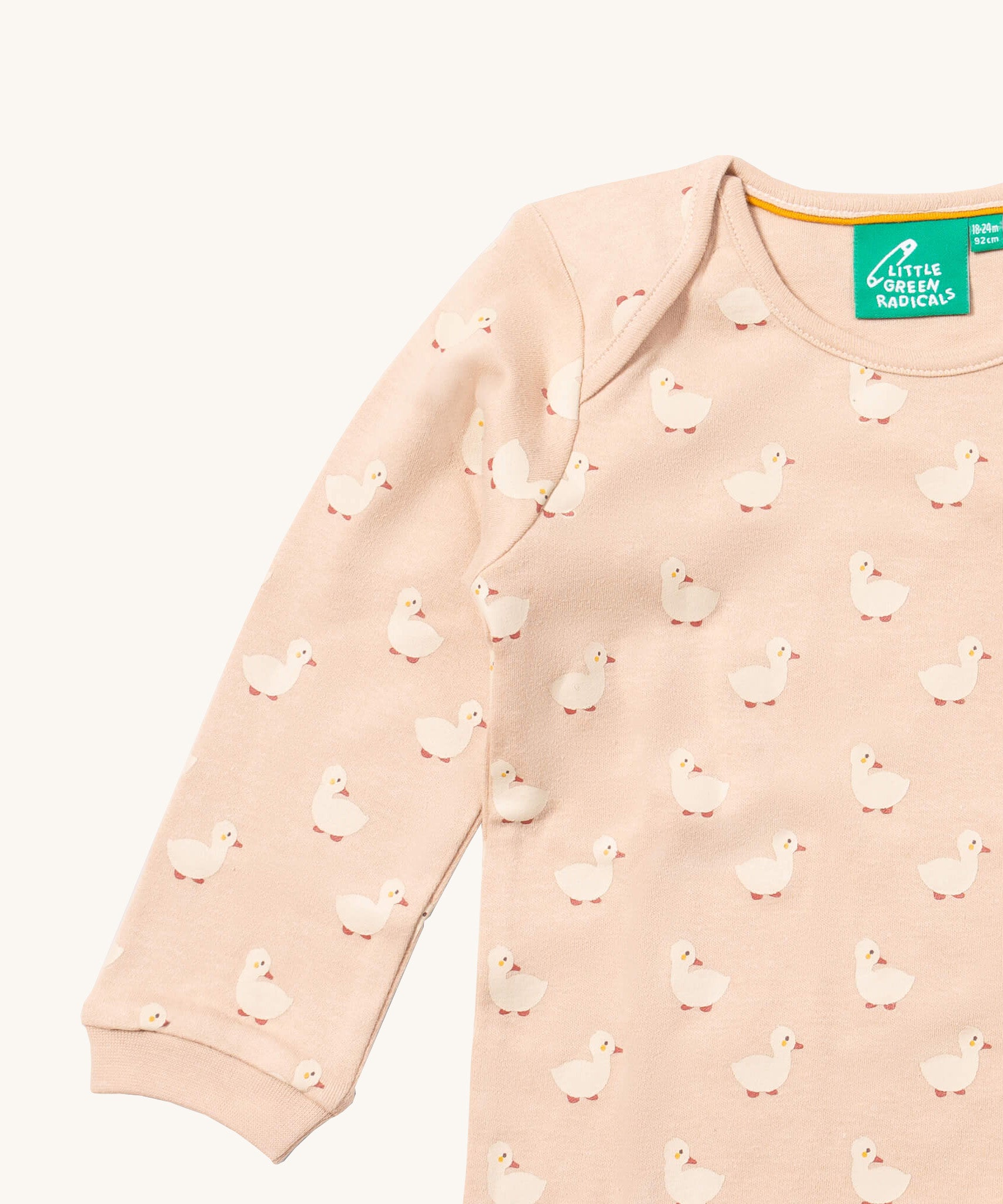 A close up of the Little Green Radicals puddle ducks sleeve t-shirt. Showing the cute duck prints collar trim detail on peach organic cotton fabric.
