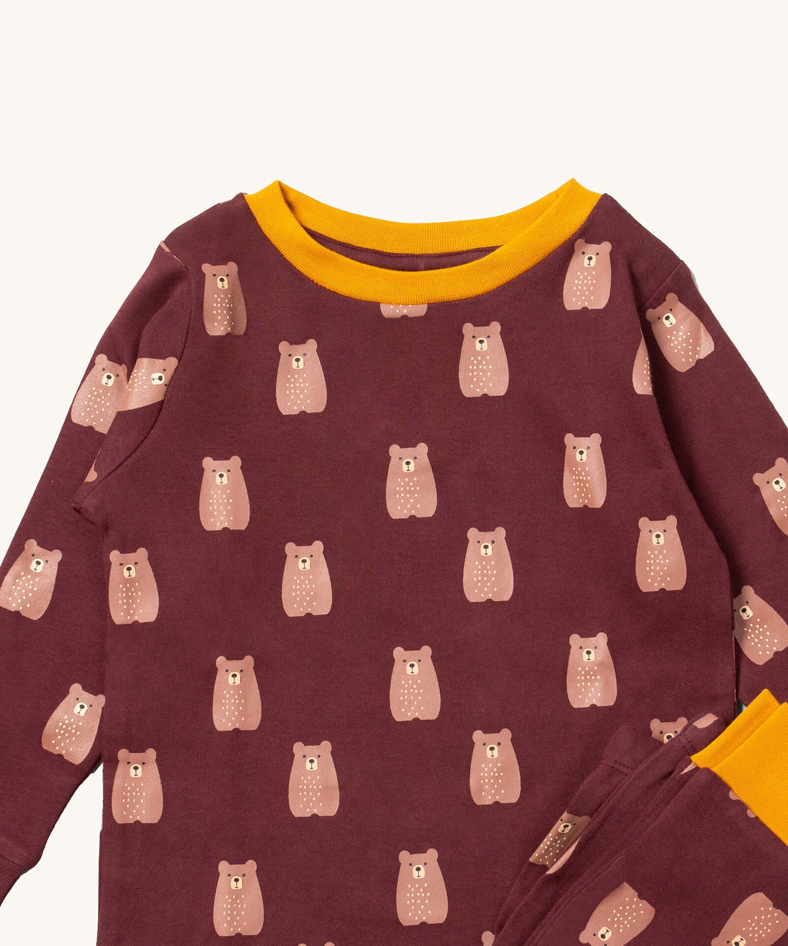 A close up of the Little Green Radicals brown bear pyjama set showing the yellow trim and brown bear detail on organic cotton fabric.
