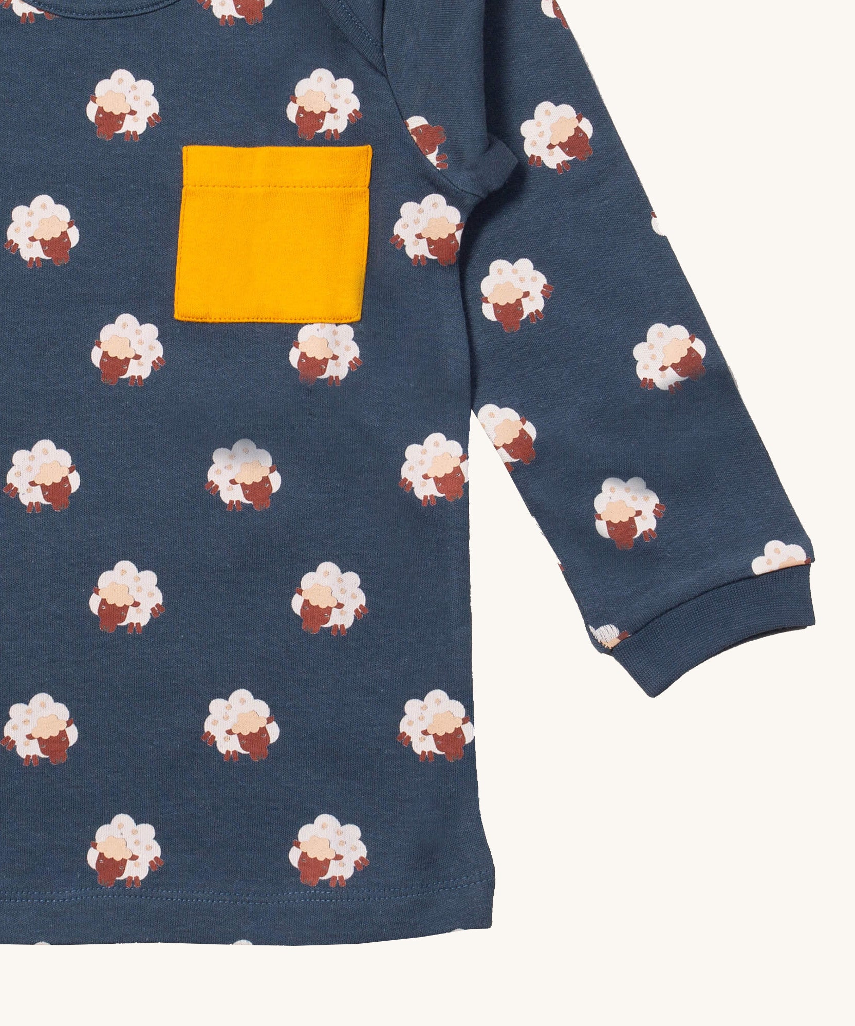 A close up of the Little Green Radicals sleeping sheep sleeve t-shirt. Showing the cute sheep print and yellow chest pocket detail on navy organic cotton fabric.
