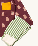 A close up of the Little Green Radicals green and cream striped jogger on top of the maroon brown bear t-shirt on organic cotton fabric
