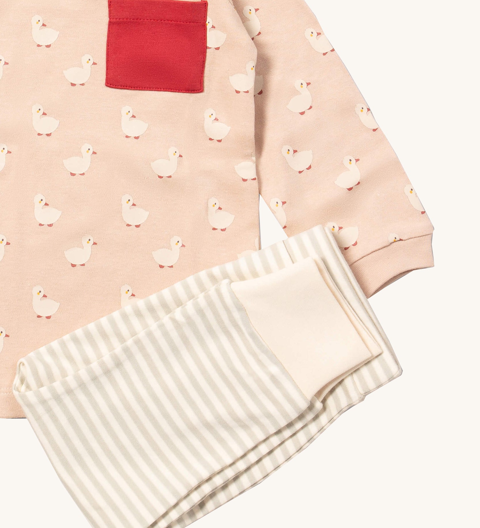 A close up of the Little Green Radicals grey and cream striped jogger on top of the puddle ducks long sleeve t-shirt on organic cotton fabric