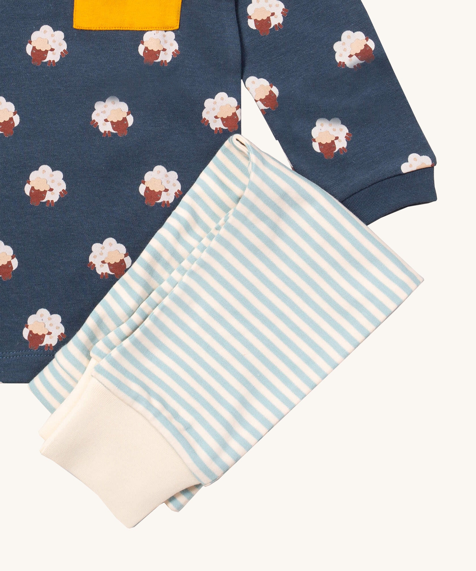 A close up of the Little Green Radicals light blue striped jogger on top of the navy sleeping sheep long sleeve t-shirt on organic cotton fabric