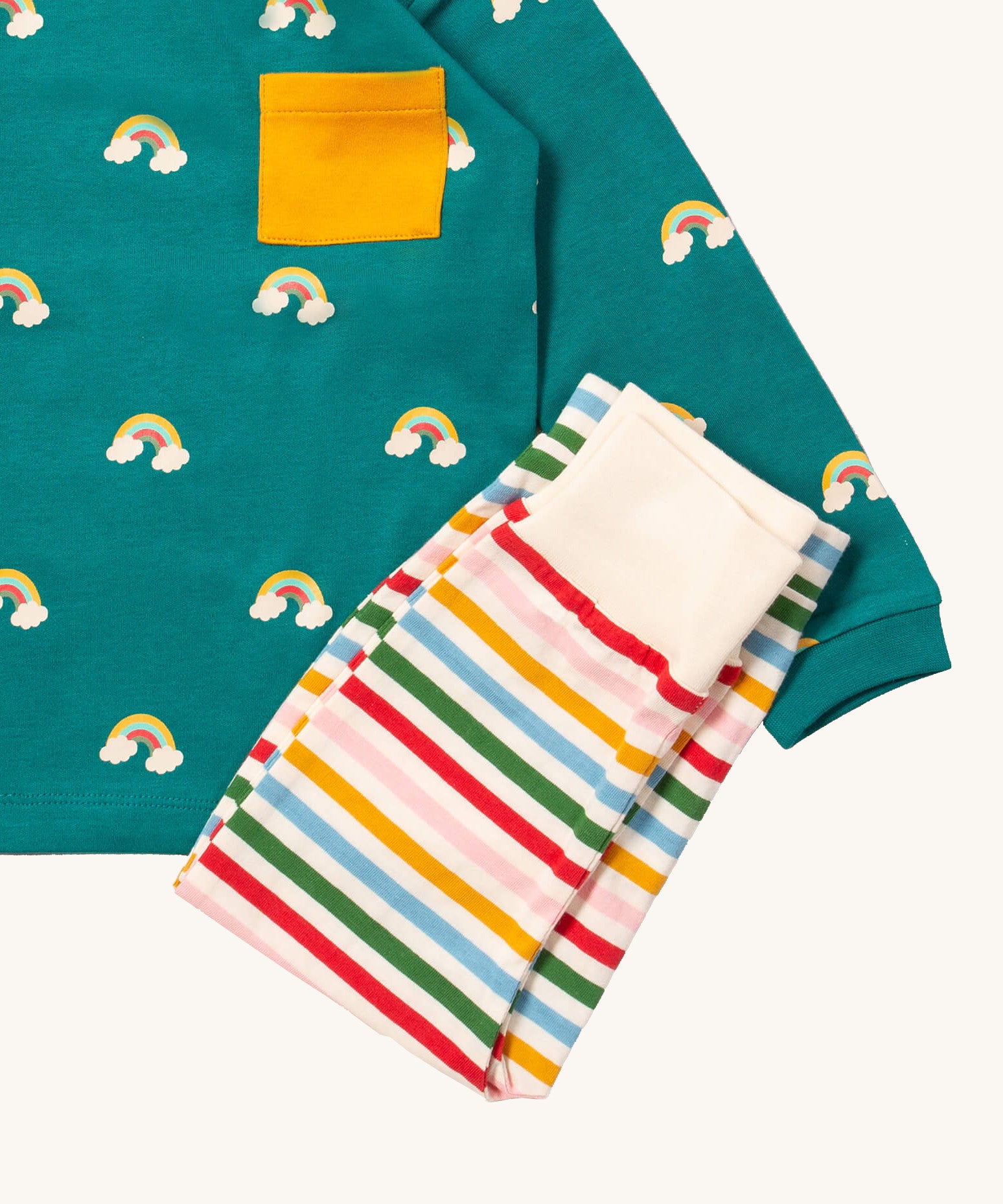 A close up of the Little Green Radicals rainbow inspired striped  jogger on top of the turquoise rainbow long sleeve t-shirt on organic cotton fabric