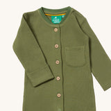 A close up of the Little Green Radicals green chive waffle playsuit showing the button fasteners and pocket detail on green organic cotton fabric