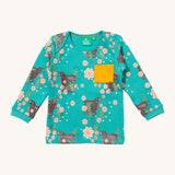 Little Green Radicals winter rabbits t-shirt available at Babipur. A GOTS organic cotton top with long sleeves in turquoise with prints of rabbits in pink flowers and a yellow chest pocket.