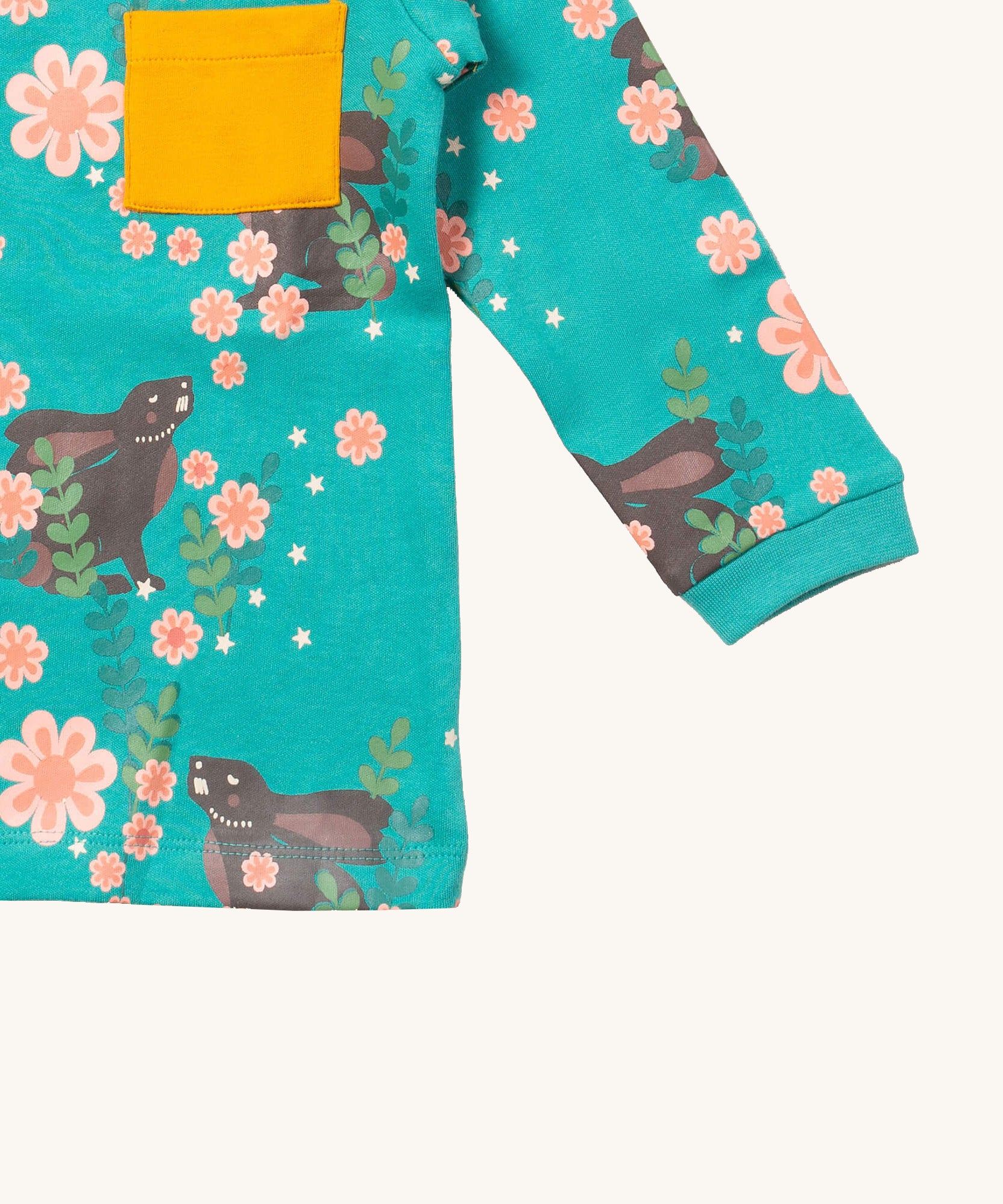 A close up of the Little Green Radicals winter rabbits long sleeve t-shirt. Showing the rabbits in pink flowers print and yellow chest pocket detail on turquoise organic cotton fabric.