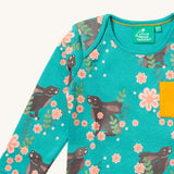 A close up of the Little Green Radicals winter rabbits t-shirt. Showing the rabbits in pink flowers print and collar trim detail.
