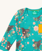 A close up of the Little Green Radicals winter rabbits t-shirt. Showing the rabbits in pink flowers print and collar trim detail.