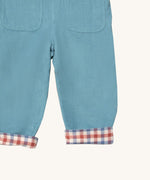 A close up of the Little Green Radicals pale blue lined corduroy dungarees  showing the back pockets and the turned up leg cuff showing the check design detail