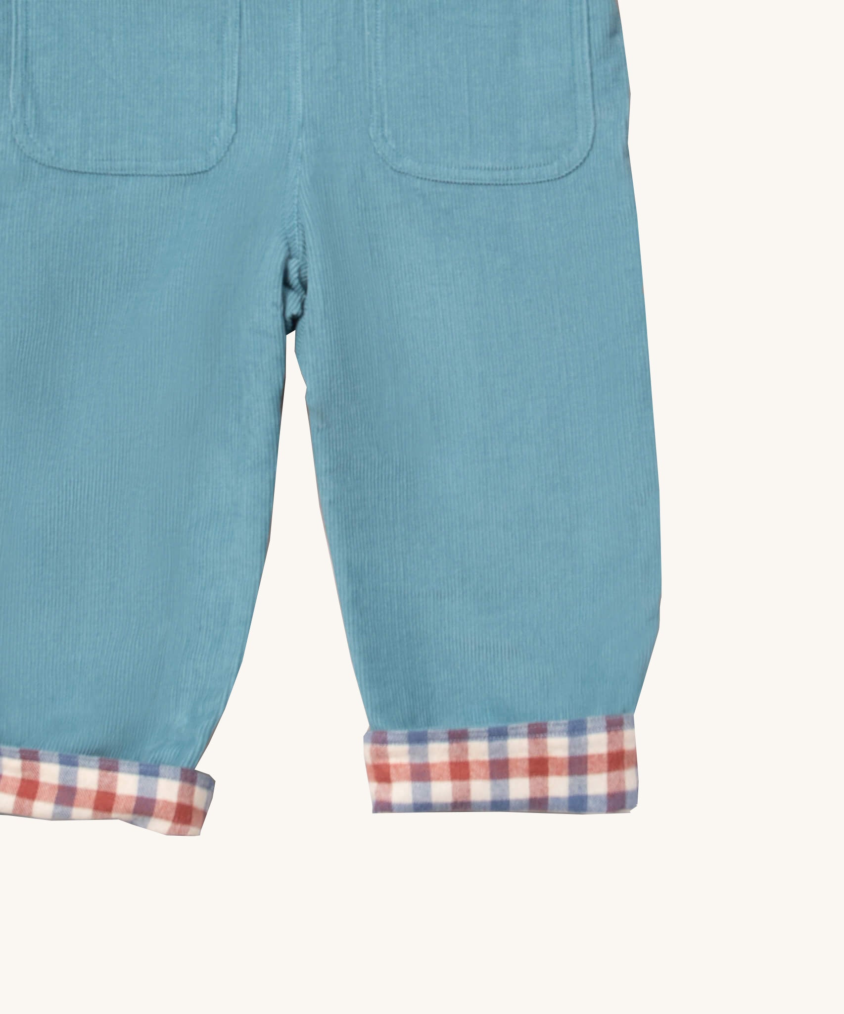 A close up of the Little Green Radicals pale blue lined corduroy dungarees  showing the back pockets and the turned up leg cuff showing the check design detail