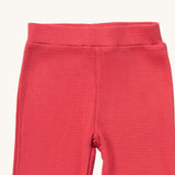 A close up of the Little Green Radicals pink berry waffle leggings showing the waffle knit detail and elasticated waist band on pink organic cotton fabric
