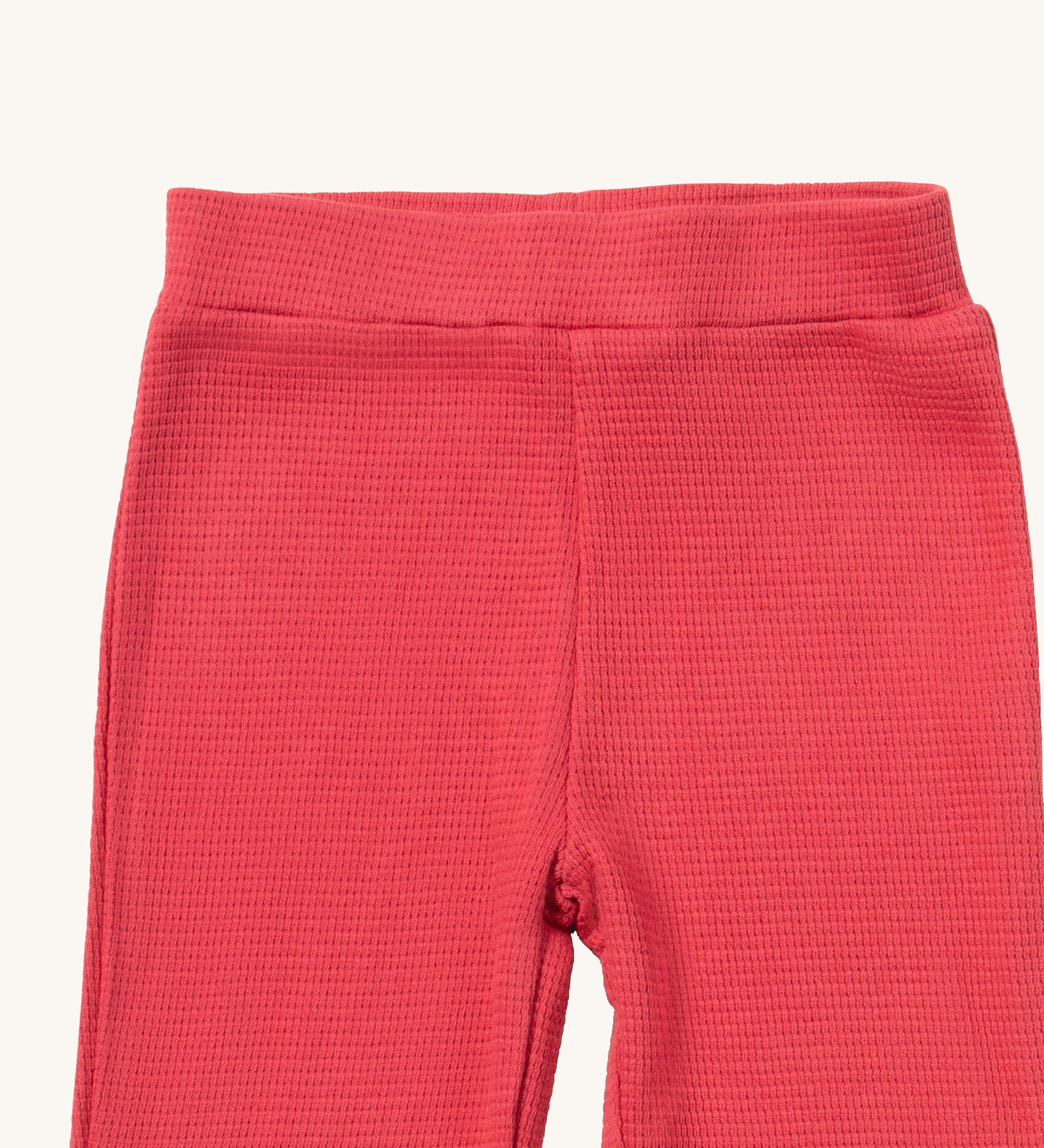 A close up of the Little Green Radicals pink berry waffle leggings showing the waffle knit detail and elasticated waist band on pink organic cotton fabric