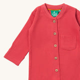 A close up of the Little Green Radicals pink waffle playsuit showing the button fastener detail and waffle detail. 