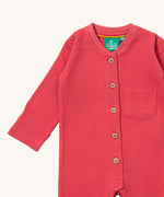 A close up of the Little Green Radicals pink waffle playsuit showing the button fastener detail and waffle detail. 