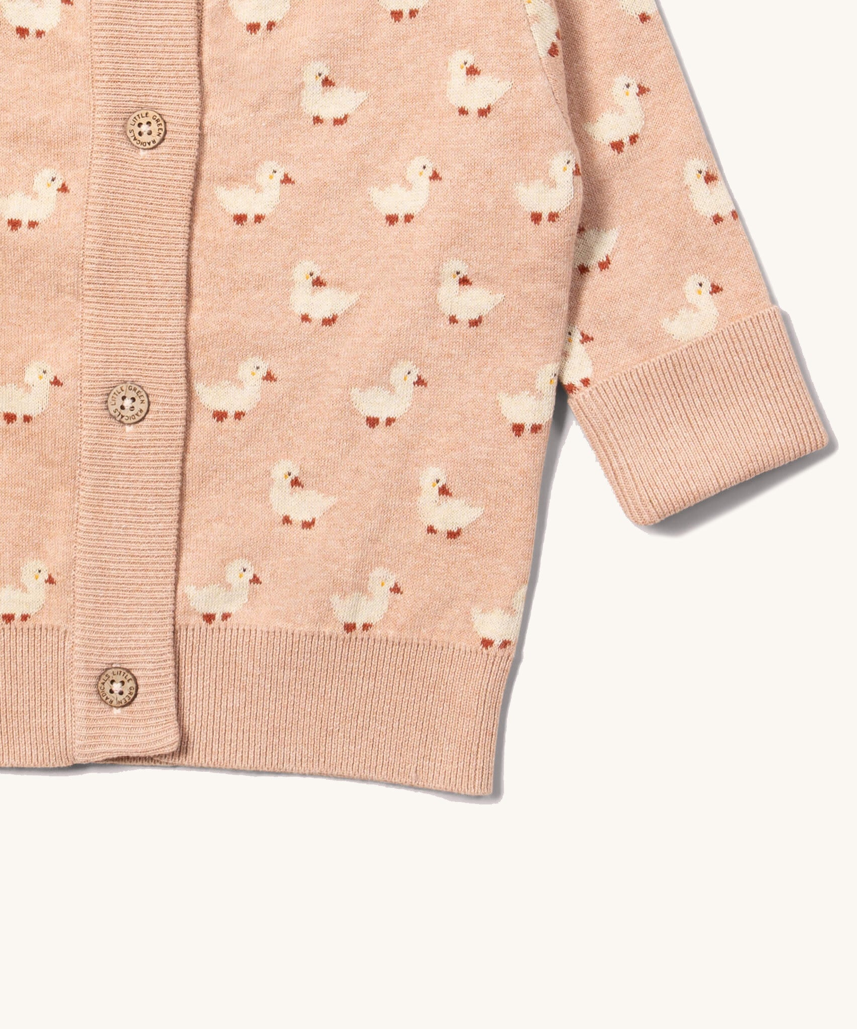 A close up of the Little Green Radicals knitted cardigan in puddle ducks showing the button detail and a close up of the white cuff and hem detail on soft pink GOTS organic cotton fabric and available at Babipur.