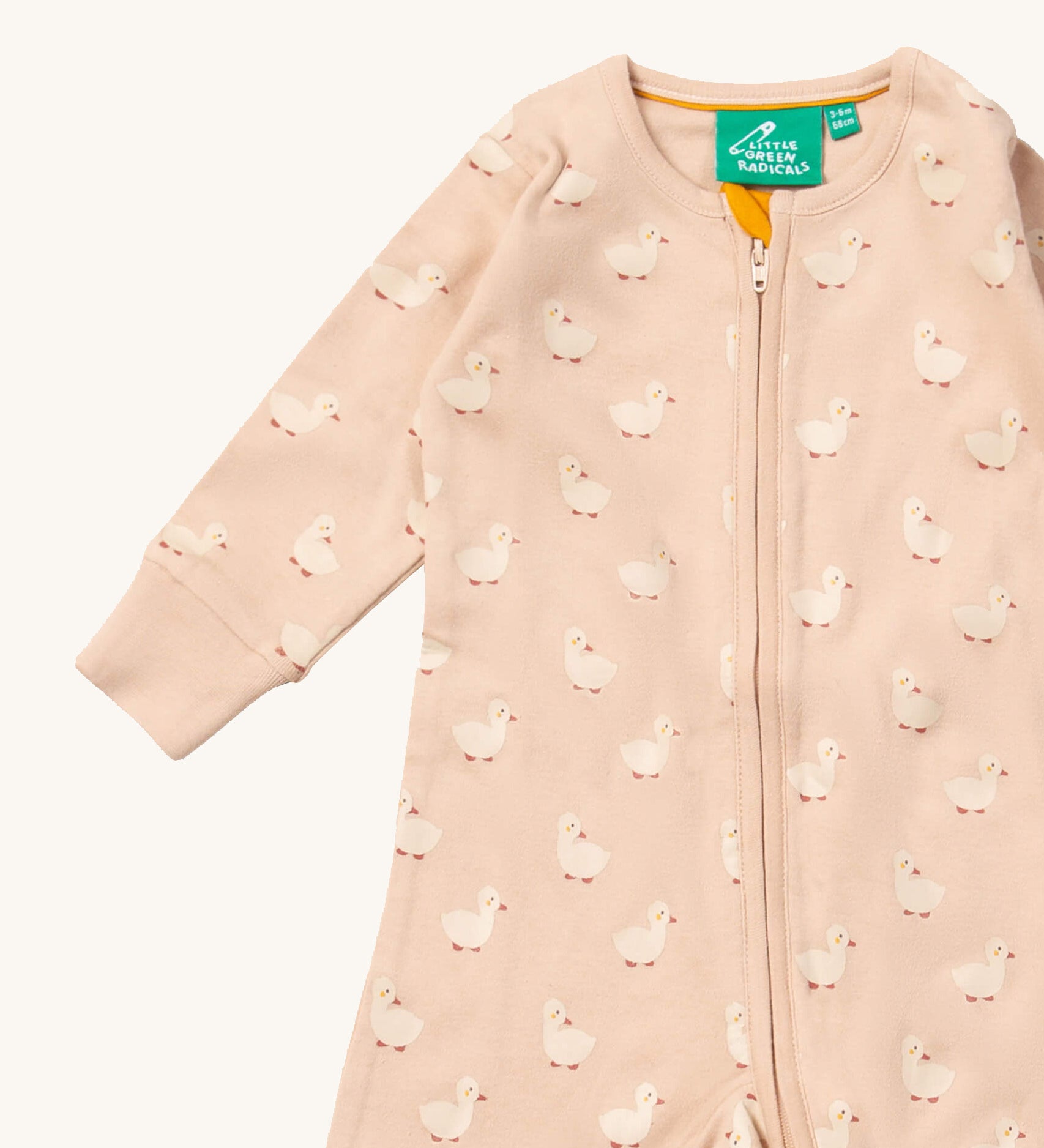 A close up of the Little Green Radicals puddle ducks baby grow, showing the full length zip detail on link pink organic cotton fabric.