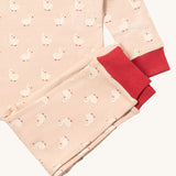 A close up of the Little Green Radicals puddle ducks pyjama set showing the red cuff trim detail and the white duck print detail on light pink organic cotton fabric.