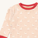 A close up of the Little Green Radicals puddle ducks pyjama top showing the elasticated red cuff and collar detail with a close up of the white puddle duck print detail on organic cotton fabric.