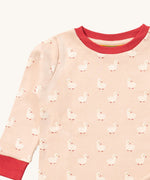 A close up of the Little Green Radicals puddle ducks pyjama top showing the elasticated red cuff and collar detail with a close up of the white puddle duck print detail on organic cotton fabric.