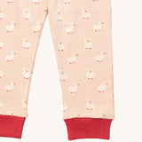 A close up of the Little Green Radicals puddle duck pyjama bottom. Showing the red cuff detail with a close up of the white duck print on light pink organic cotton fabric.