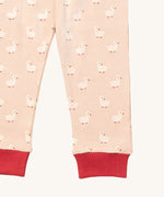 A close up of the Little Green Radicals puddle duck pyjama bottom. Showing the red cuff detail with a close up of the white duck print on light pink organic cotton fabric.