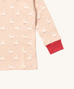 A close up of the Little Green Radicals puddle ducks top showing the red elasticated cuff detail with a close up of the white duck print on light pink organic cotton fabric.