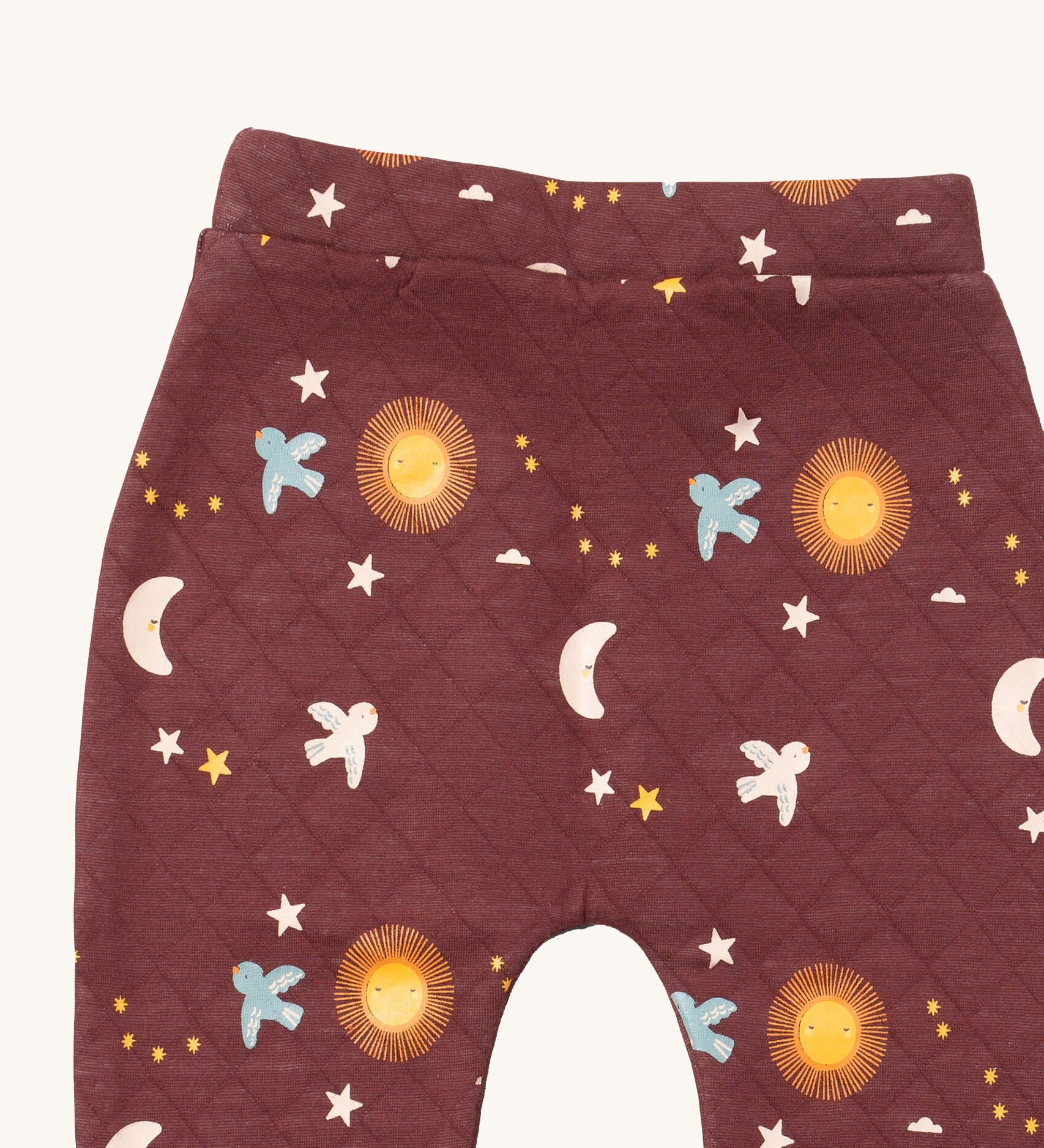 A close up of the Little Green Radicals flying birds quilted joggers. Showing the quilted stitch and flying prints detail on dark maroon organic cotton fabric.