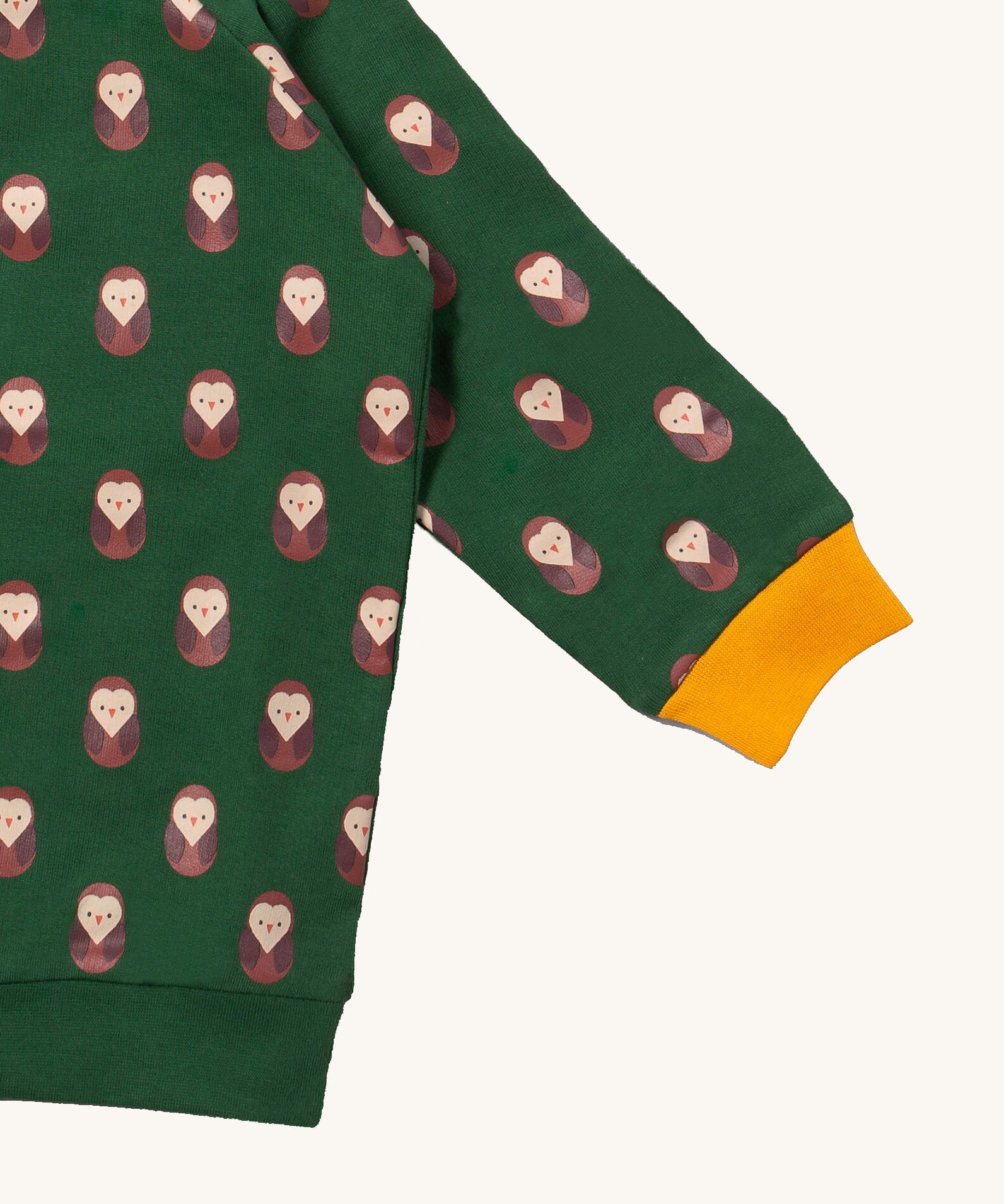 A close up of the Little Green Radicals brown owl raglan sweatshirt showing the yellow cuff detail and brown owl print on green organic cotton fabric.