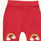 A close up of the Little Green Radicals soft red rainbow kneepatch joggers showing the rainbow embroidery kneepatch detail on pale red organic cotton fabric.