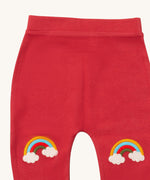 A close up of the Little Green Radicals soft red rainbow kneepatch joggers showing the rainbow embroidery kneepatch detail on pale red organic cotton fabric.