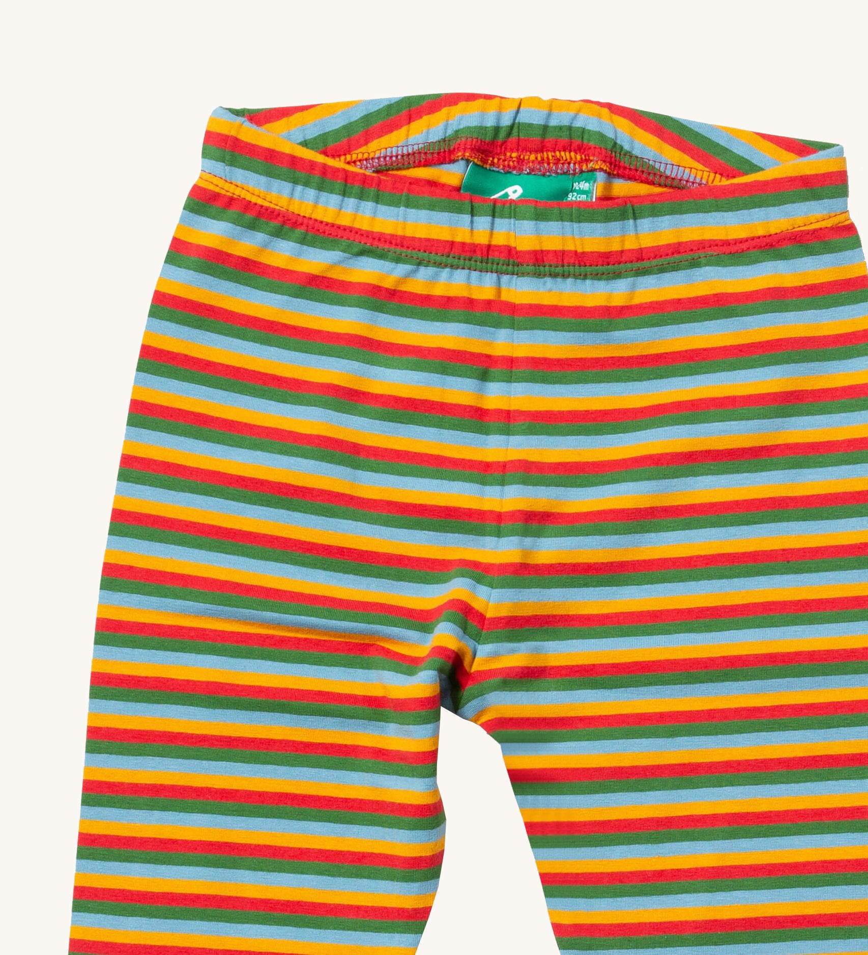 A close up of the Little Green Radicals rainbow striped organic leggings. Showing the elasticated detail and rainbow striped design on organic cotton fabric