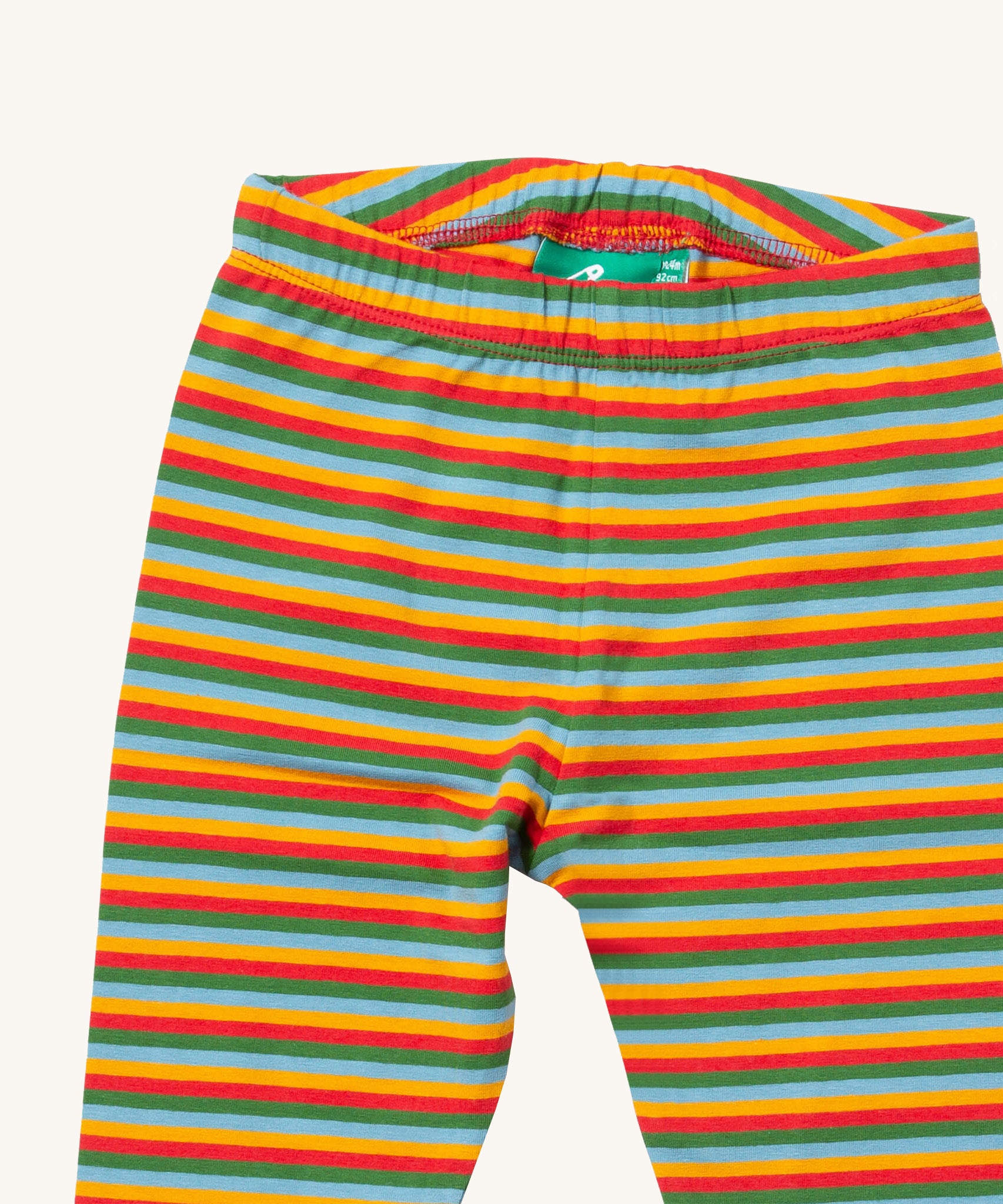 A close up of the Little Green Radicals rainbow striped organic leggings. Showing the elasticated detail and rainbow striped design on organic cotton fabric